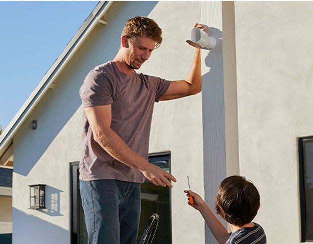 Une homme et son fils installent facilment une caméra de sécurité devant leur maison